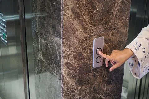 A person is pressing the button to call an elevator in a lobby Stock Photos