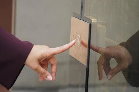 Person pressing elevator button in a modern building lobby Stockfoto's