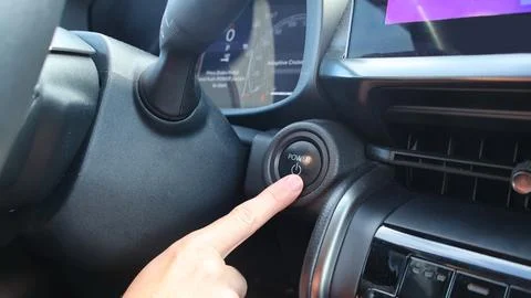 Person pressing power ignition button in modern car Stock Photos