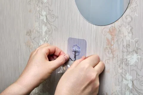 Person is pressing transparent adhesive patch with plastic hook onto vertic.. Stock Photos