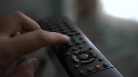 A person pressing the volume button on a remote control in slow motion Stock Footage 339959594