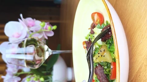 Person pricks a peace of beef on a fork. Eating warm salad. Vertical video Stock Footage 264963955