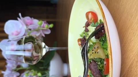 Person pricks piece of meat on a fork. Eating warm salad. Vertical video. Close Stock Footage 264963964