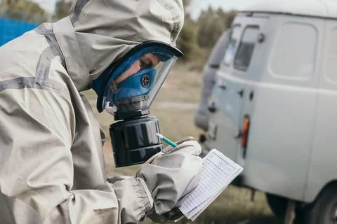 Person in protective gear taking notes while standing near a white vehicle Stock Photos