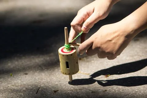 Person pulling green string to launch traditional Indonesian bamboo spinnin.. Stock Photos