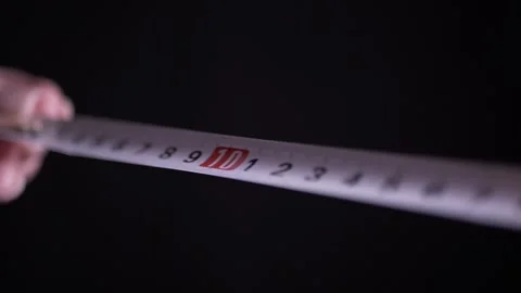 Person Pulling Retractable Tape Measure on Black Studio Background 库存影片 338998455