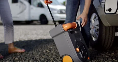 Person Pulling a Rolling Suitcase Across a Gravel Parking Lot Stock Footage 340282880