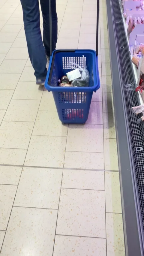 Person pulling shopping basket trolley in supermarket aisle moving away from cam Stock Footage 331593064
