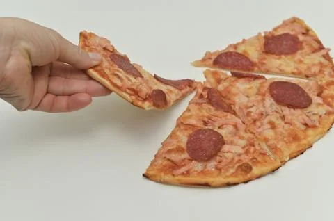 Person pulls apart a slice of pepperoni pizza, revealing the melted cheese... Stock Photos