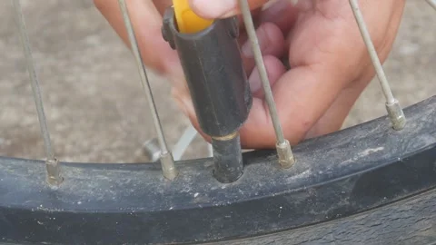 A person is pumping up a bicycle tire using a manual hand pump outdoors. Stock Footage 332866879