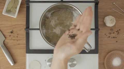 Person puts black pepper in boiling water in metal pan on kitchen 스톡 동영상 113214908