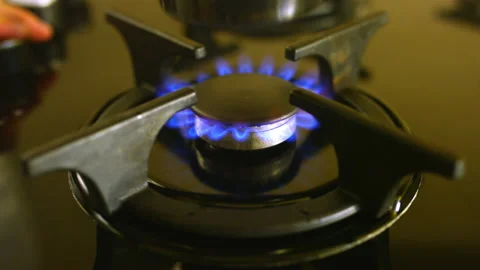 Person puts coffeemaker on black burner with blue flame Stock Footage 232202942