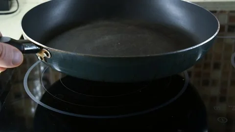 Person puts empty frying pan on stove Stock Footage 149872831