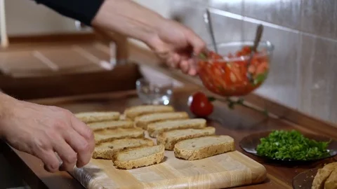 The person puts the ingredients on top of the bread for cooking bruschetta Stock Footage 73920752