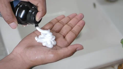 Person puts saving foam on one hand while standing at a sink Stock Footage 337143348