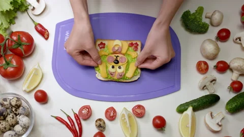 Person puts small pieces of cheese on vegetable sandwich Stock Footage 237004691
