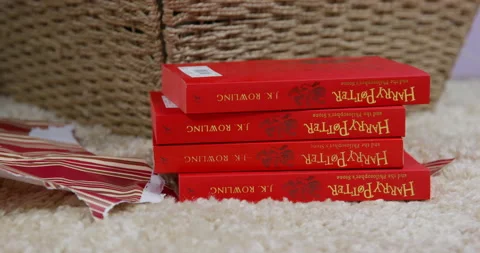 Person puts a stack of identical Harry Potter softcover books on the carpet and Stock Footage 220817351