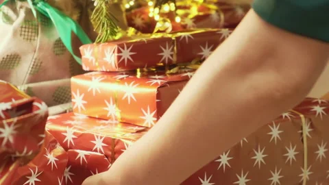 Person puts stack of presents in boxes under Christmas tree Stock Footage 216937926