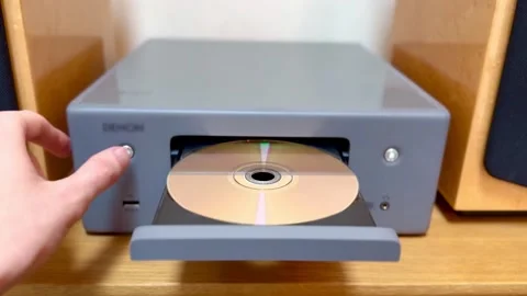 Person putting disc into cd player music stereo then pushing close tray button Stock Footage 328358362