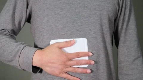 A person putting a disposable heat pack on their stomach. Stock Footage 336670524