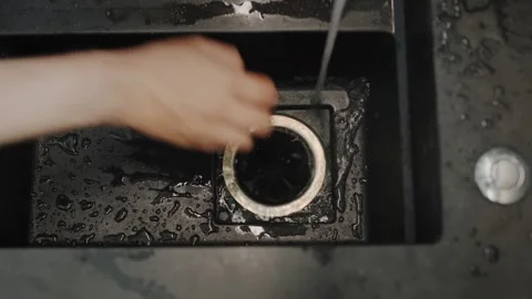 Person putting vegetable scraps into a kitchen sink garbage disposal unit. Stock Footage 334590454
