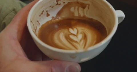 Person raises half full cup of coffee to drink Stock-Footage 107787928