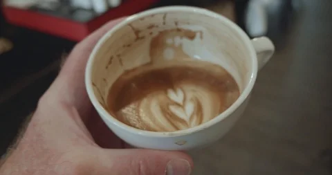 Person raises half full cup of coffee to drink Stock-Footage 107813612