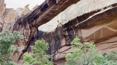 Person rappelling between cliff and natural arch in Moab Utah Stock Footage 186894269