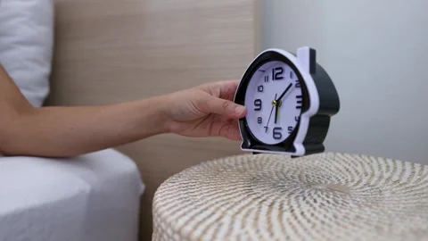 Person Reaching for Alarm Clock on Bedside Table in Morning Stock Footage 332966976