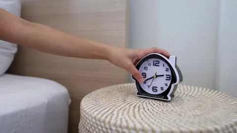 Person Reaching for Alarm Clock on Bedside Table in Morning Stock Footage 332967302