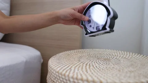 Person Reaching for Alarm Clock on Bedside Table in Morning Stock Footage 333604701