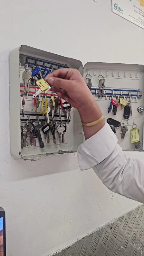 A person reaching into an open wall-mounted metal key cabinet box to safely Video stock 346098031