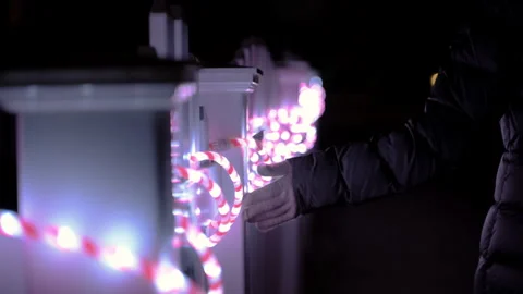 Person reaching out and touching colorful string lights at night. Close up of Stock Footage 330985086