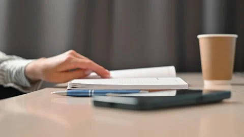 A person is reading and taking notes at a desk. The workspace features notebooks Stock Footage 339005820