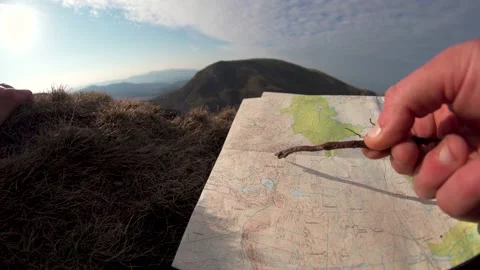 A person reading a map in the mountains using a stick to plot a route Vídeos de archivo 200817153