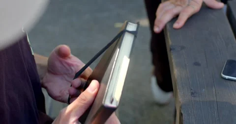 A person reads at a rustic table, sharing space with a man Stock Footage 324612294