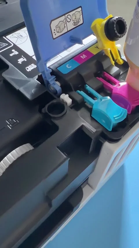 A person refilling a Canon MAXIFY printer ink tank with a yellow bottle. Stock Footage 337615750