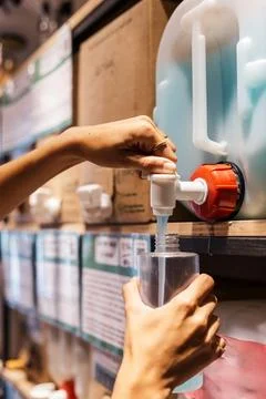 Person refilling detergent bottle at zero waste store Stock-Fotos