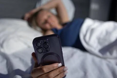 Person Relaxing in Bed While Using a Smartphone at Night Stock Photos