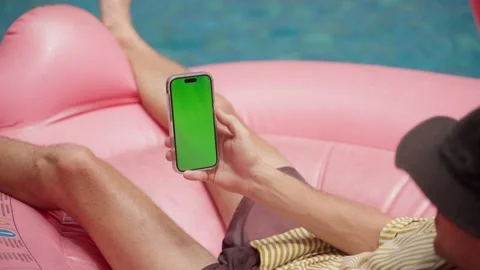 Person Relaxing on Pink Pool Float With Green Screen Smartphone in Hand Stock Footage 267785652