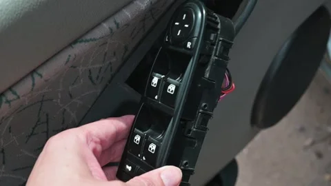 A person is removing a car window switch assembly from the door panel. Stock Footage 339004571