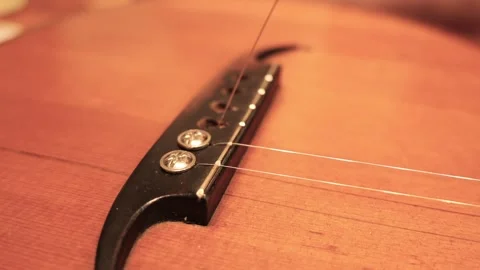 Person replacing a broken string on an acoustic guitar bridge Stock Footage 341376407
