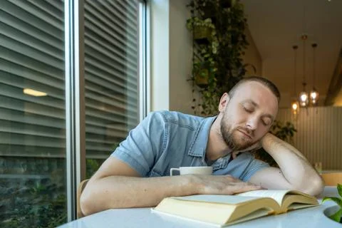 Person resting with head on table while studying at home in a cozy corner w.. Stockfoto's