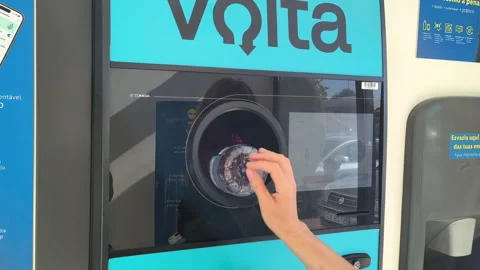 Person returning empty plastic bottles into an automated recycling machine in Видео 345833174