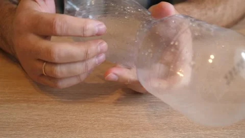 Person rhythmically tapping fingers on an empty plastic bottle in close up on Stock Footage 341193897