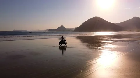 Person rides motorbike on the beach Stock Footage