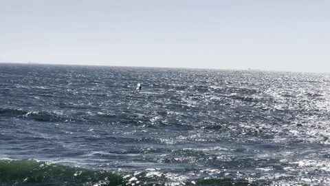 Person rides the ocean waves with a wing sail, moving smoothly across the s.. Stock Footage 319662560