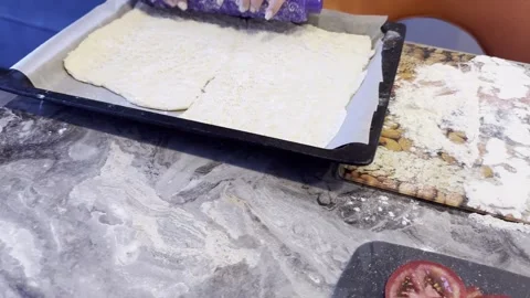 A person is rolling out dough on a table with a purple rolling pin Stock Footage 283488086