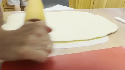 Person rolling out dough into a thin rectangular shape for baking Stock Footage 318554288