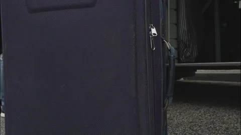 Person rolls dark blue suitcase with zipper and part of handle Stock Footage 326875024